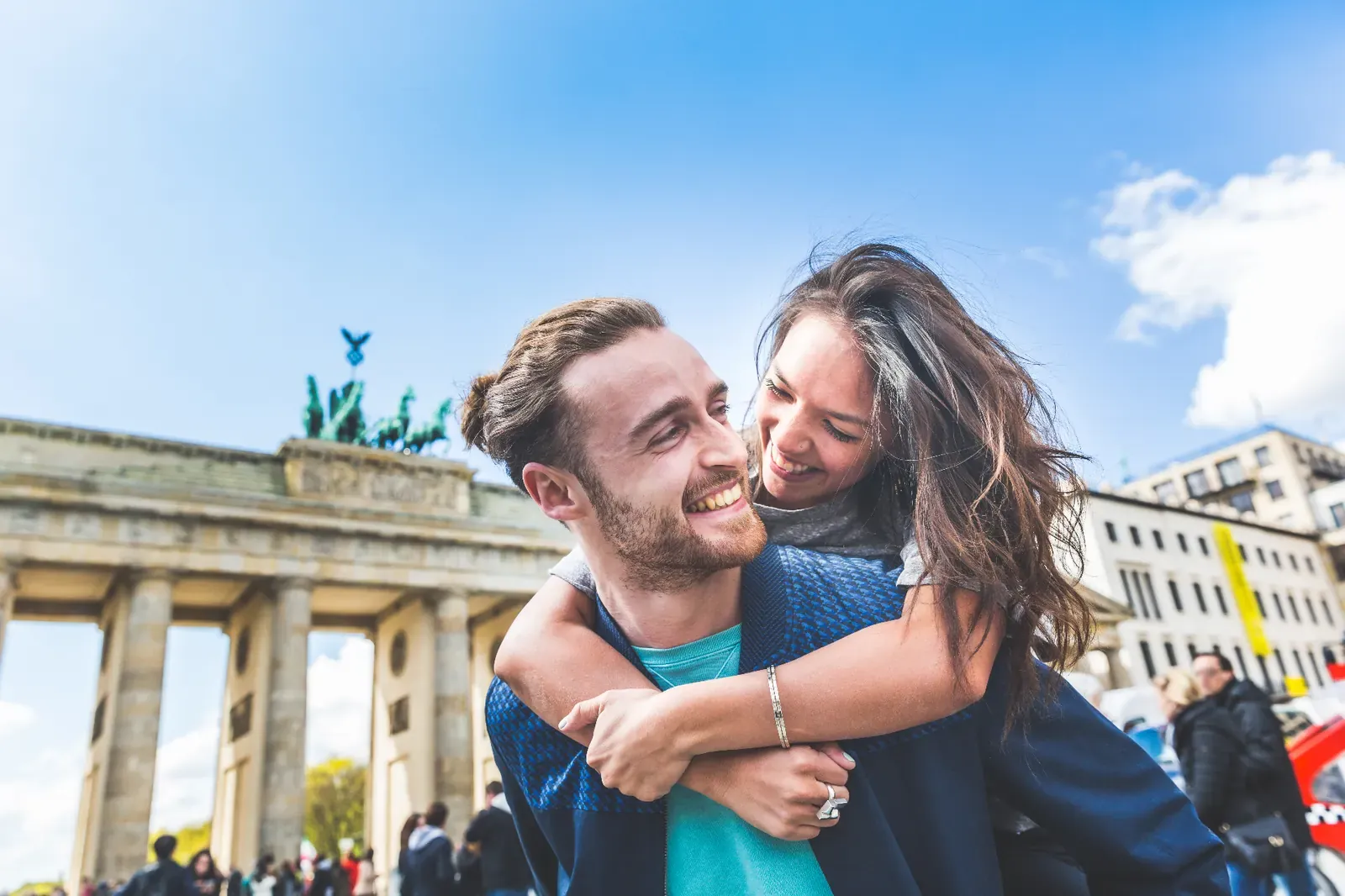 A young international couple laughing together in front of the Brandenburg Gate in Berlin